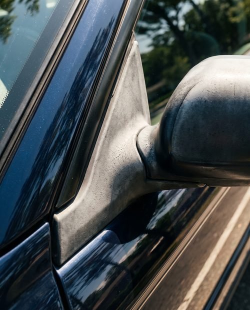 Sun-faded chalky grey plastic trim beside glossy dark paint.
