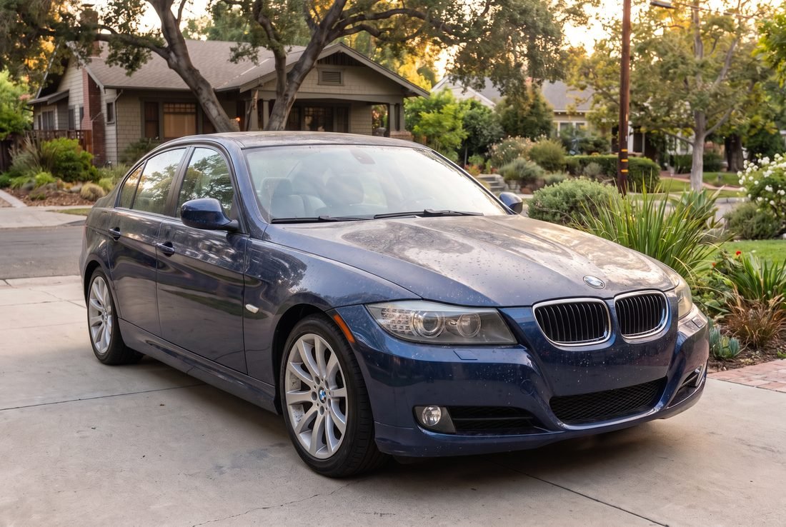 A dark blue BMW 3-Series covered in a dull layer of road film and rain spotting.